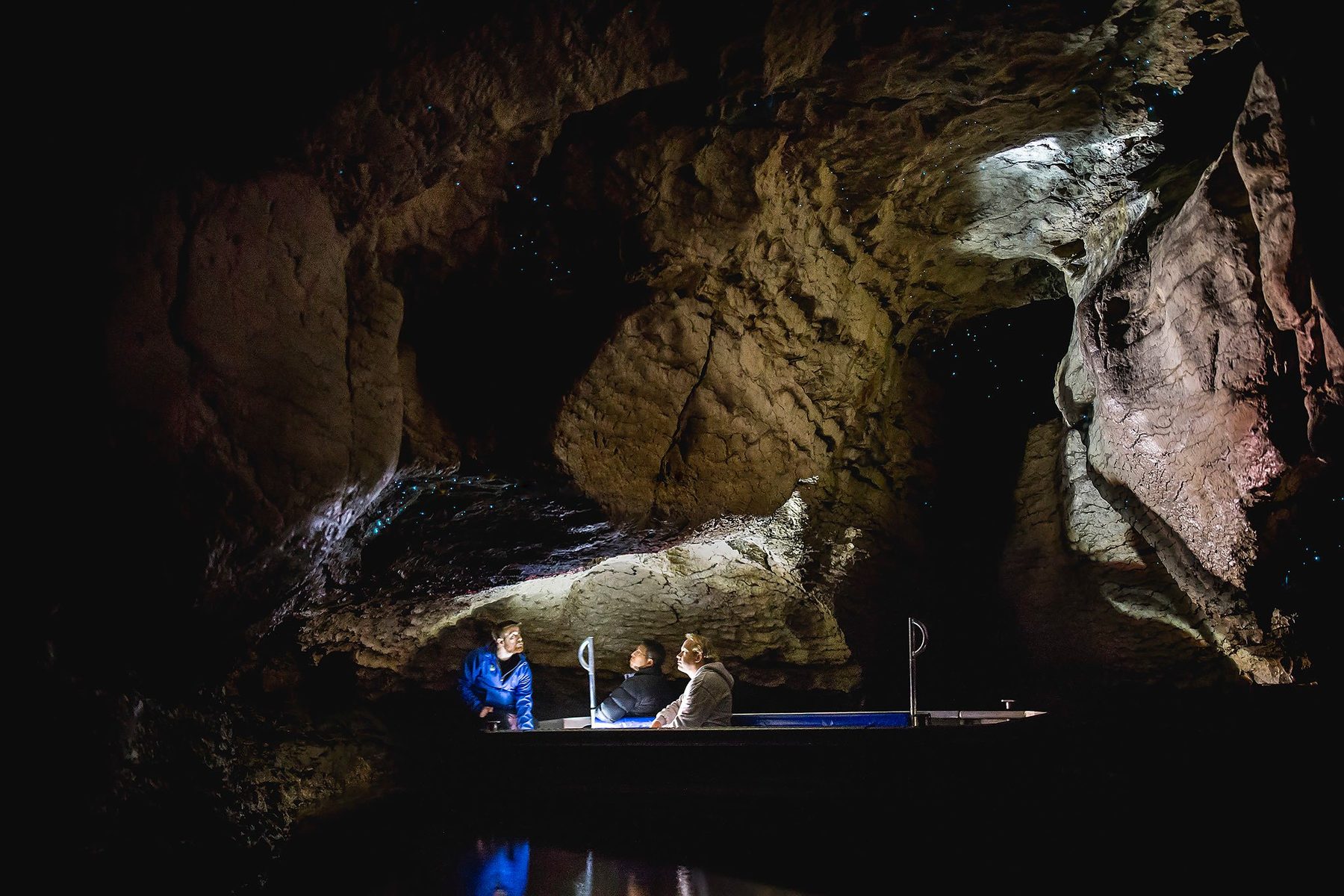 Small guided boat moving through a high limestone chamber